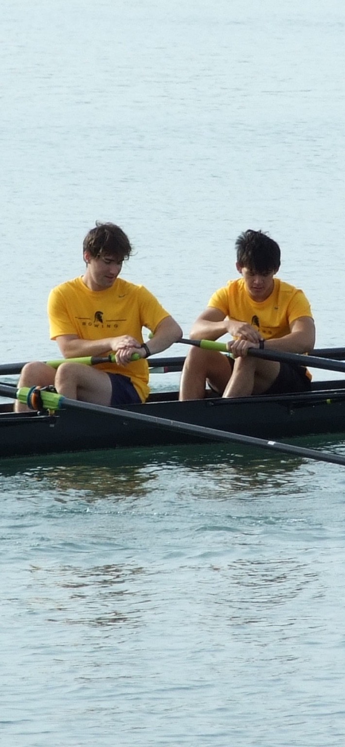 Two Waterloo rowers in yellow shirts sitting in a rowing boat
